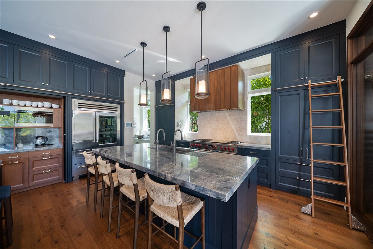Detailed view of dark cabinetry, stone counters, and brass ladder